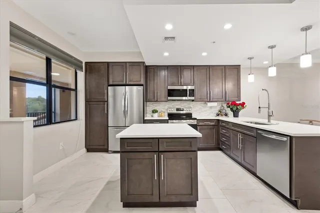 a kitchen with kitchen island granite countertop a sink stainless steel appliances and counter space