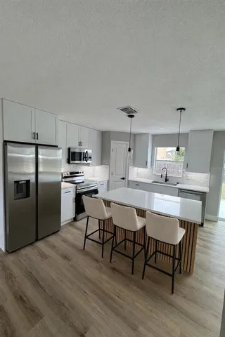 a kitchen with stainless steel appliances a dining table chairs and wooden floor
