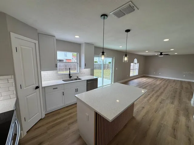 a open kitchen with a sink a refrigerator and wooden floor