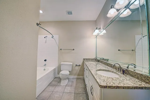 a bathroom with a granite countertop sink a toilet and shower