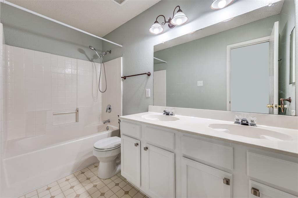 8405 Seven Oaks Lane Denton, TX 76210 - Photo 7 of 11 a bathroom with a sink a toilet and a large mirror