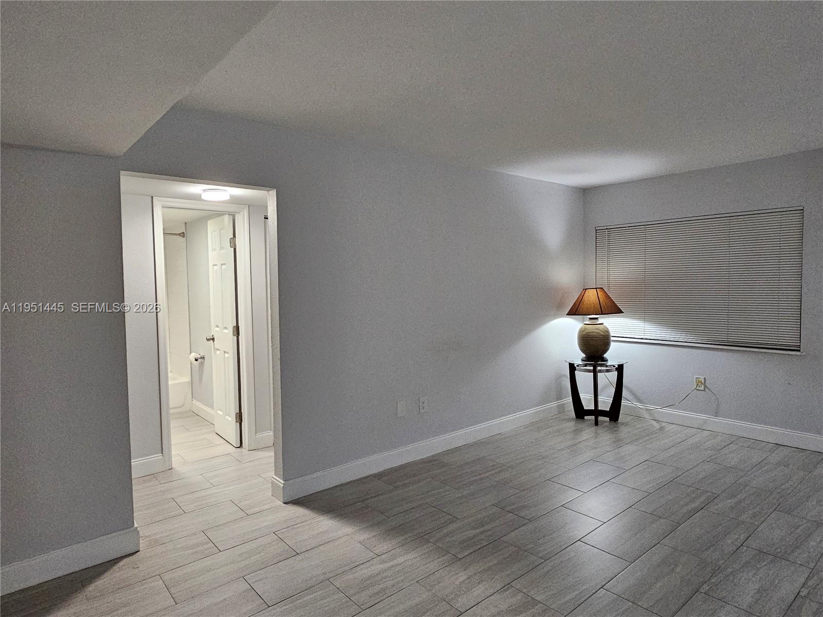 8075 Southwest 107th Avenue, Unit 114 Miami, FL 33173 - Photo 4 of 18 a view of a room with wooden floor a table and a potted plant