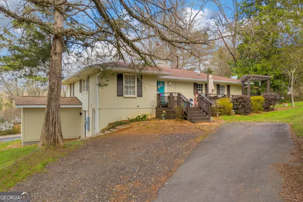 a front view of a house with large trees and plants