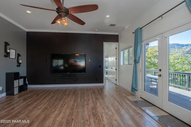a view of empty room with wooden floor and fan