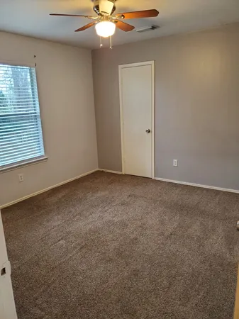 an empty room with a chandelier fan and windows