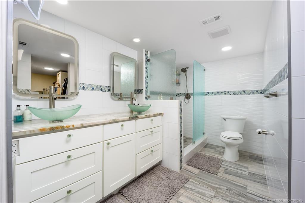 3100 Southeast Pruitt Road, Unit E204 Port St. Lucie, FL 34952 - Photo 14 of 40 a spacious bathroom with a granite countertop sink a toilet a mirror and shower