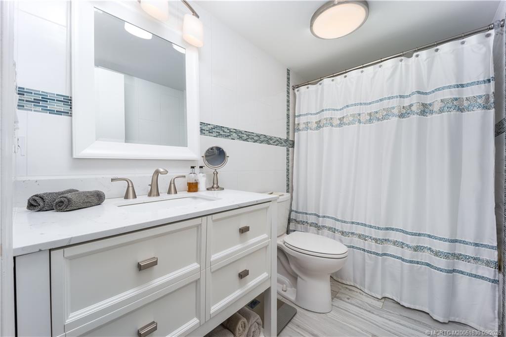 3100 Southeast Pruitt Road, Unit E204 Port St. Lucie, FL 34952 - Photo 18 of 40 a bathroom with a granite countertop sink a toilet and a mirror