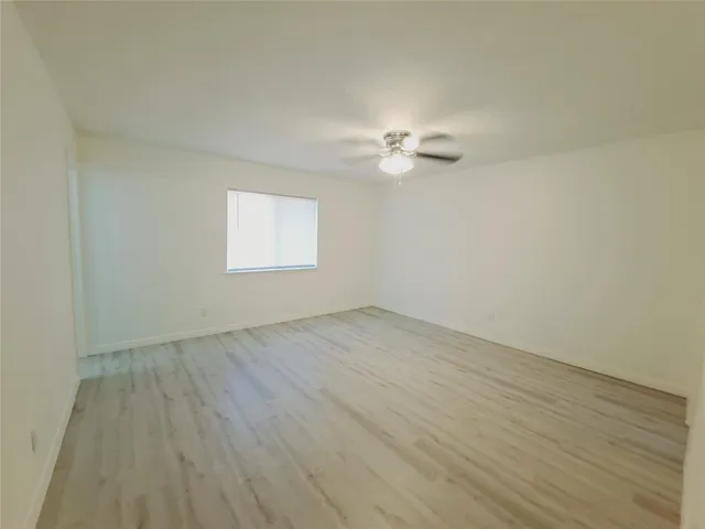 an empty room with wooden floor and window
