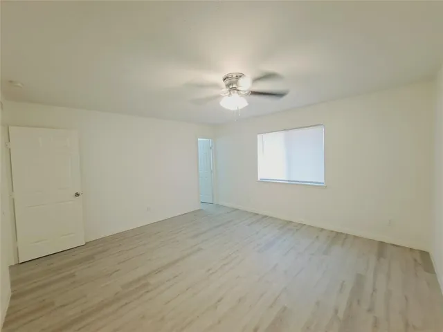 an empty room with wooden floor and ceiling fan