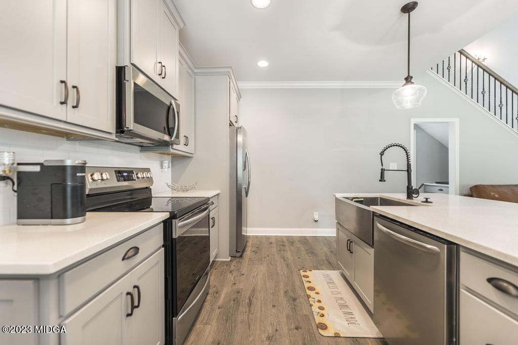 129 Timber Ridge Circle Byron, GA 31008 - Photo 15 of 42 a kitchen with stainless steel appliances a sink dishwasher a stove top oven a refrigerator with wooden floor and cabinets