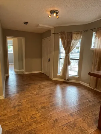 an empty room with wooden floor and windows