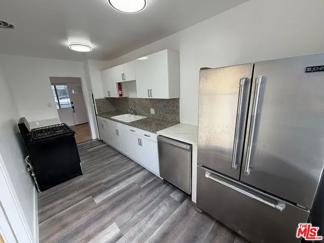 a kitchen with granite countertop a refrigerator stove and sink