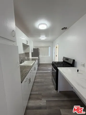 a large kitchen with kitchen island a sink dishwasher stove with wooden floor and cabinets