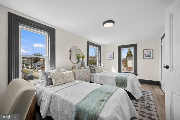 a bedroom with two beds and a large mirror next to a window