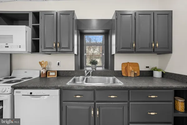 a kitchen with granite countertop a sink a stove and cabinets