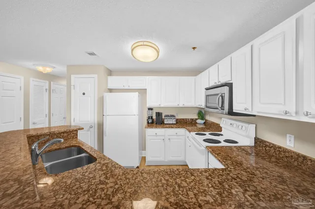 a kitchen with granite countertop a refrigerator stove top oven and sink