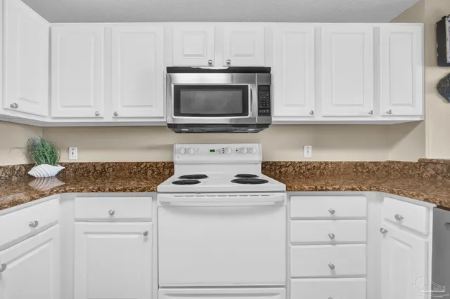 a kitchen with granite countertop white cabinets and stainless steel appliances