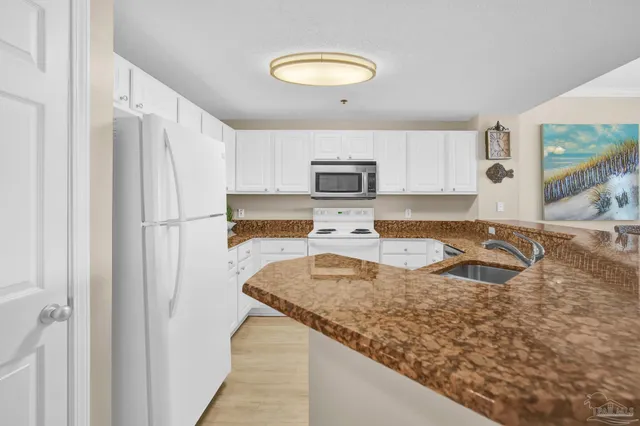a kitchen with granite countertop a sink a counter top space and cabinets