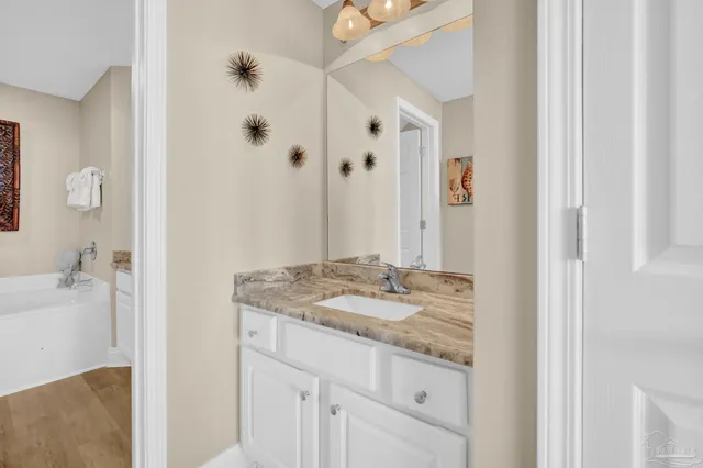 a bathroom with a granite countertop sink a mirror and shower