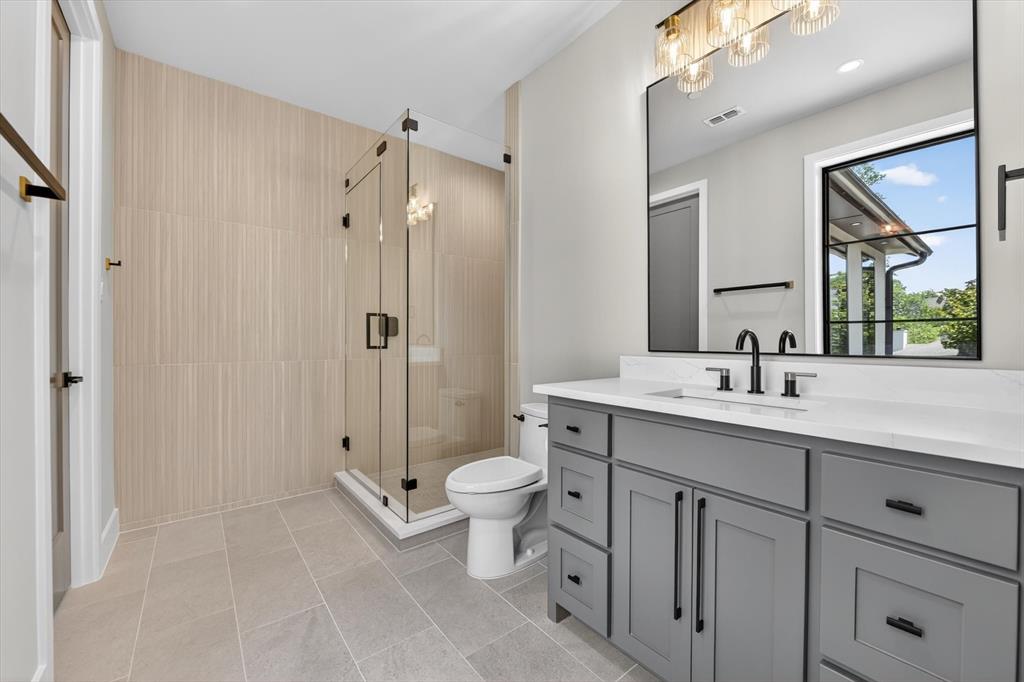 11028 Edgemere Road Dallas, TX 75230 - Photo 33 of 40 Contemporary bathroom featuring a spacious glass-enclosed shower, a gray vanity with a white countertop, and modern black hardware