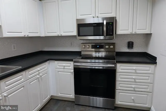 a kitchen with stainless steel appliances granite countertop white cabinets and a stove a oven with white countertops