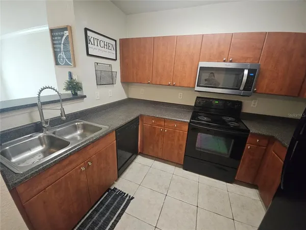 a kitchen with granite countertop a sink stove and microwave