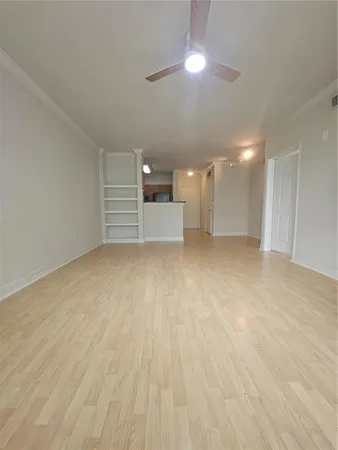 a view of empty room with wooden floor and ceiling fan
