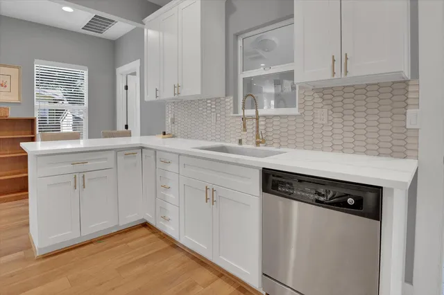 a kitchen with a sink dishwasher and white cabinets