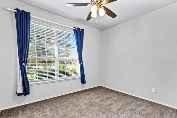 a view of an empty room with wooden floor and fan