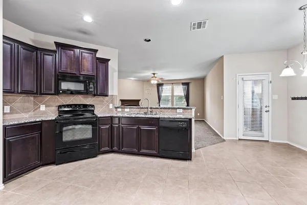 a kitchen with granite countertop a stove top oven sink and cabinets