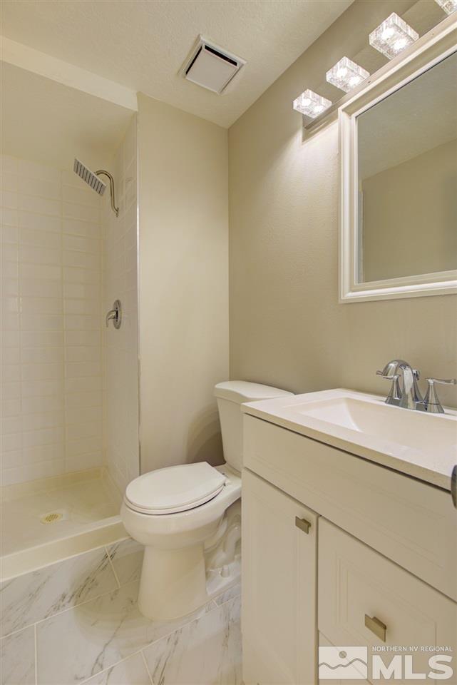 6755 Lotus Street Reno, NV 89506 - Photo 13 of 27 a bathroom with a granite countertop sink mirror vanity and toilet