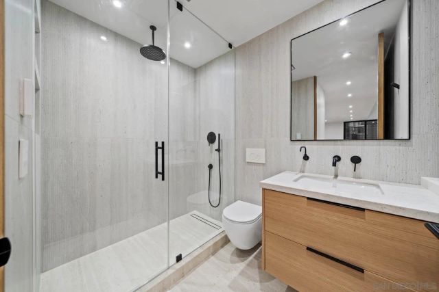 a spacious bedroom with a bed and a flat tv screen on dresser