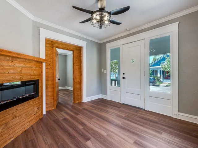 a view of a livingroom with wooden floor a ceiling fan and a kitchen