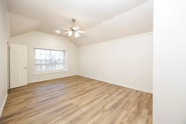 an empty room with wooden floor and fan