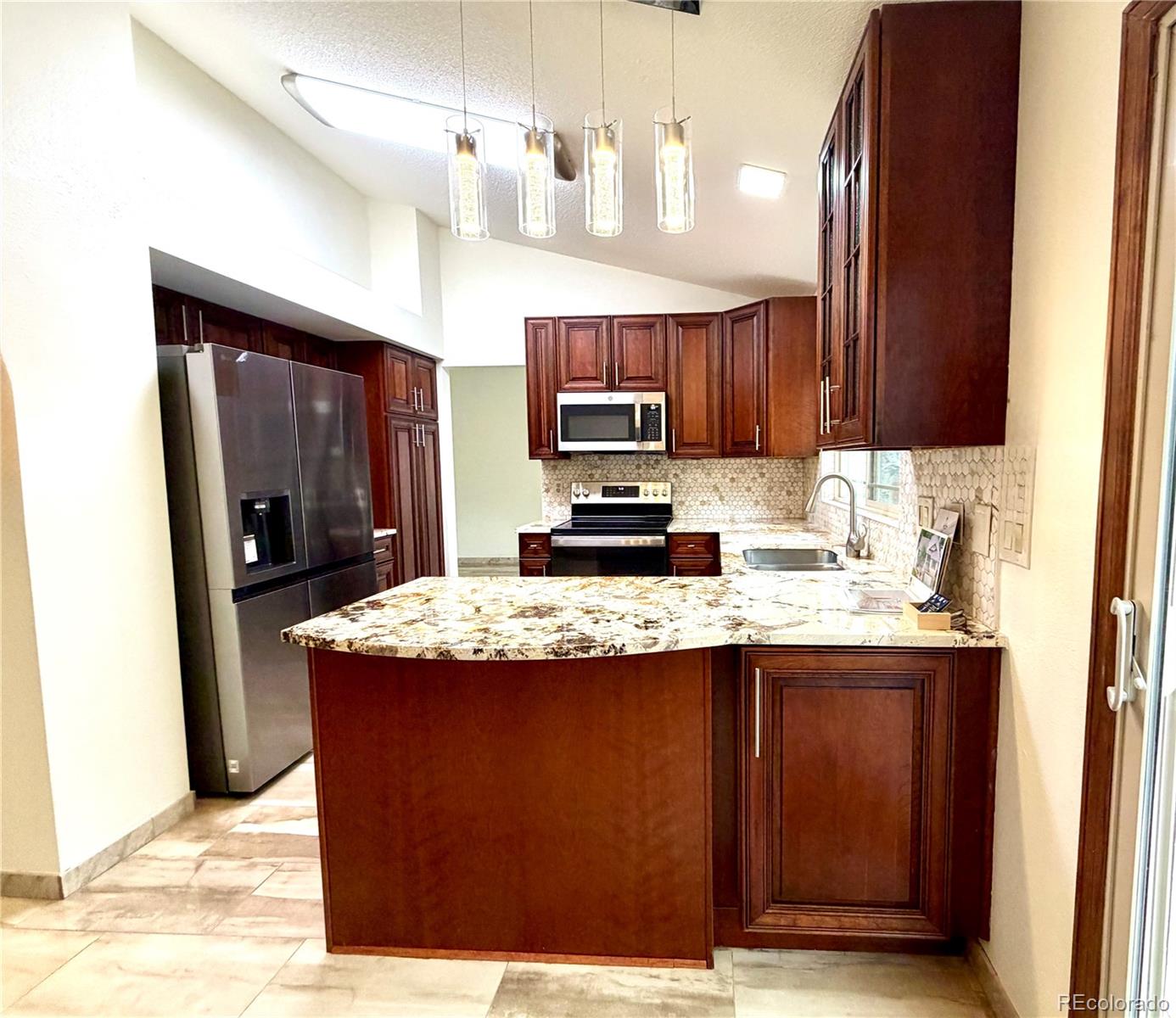8725 Meadowlark Circle Highlands Ranch, CO 80126 - Photo 11 of 40 a kitchen with kitchen island granite countertop a sink stove and refrigerator