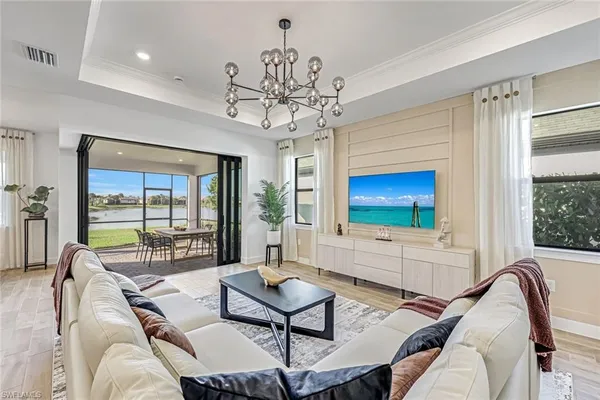 a living room with furniture a chandelier and a floor to ceiling window