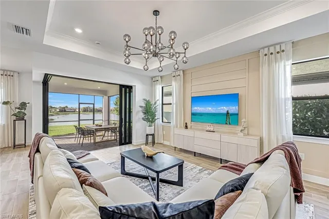 a living room with furniture a chandelier and a floor to ceiling window
