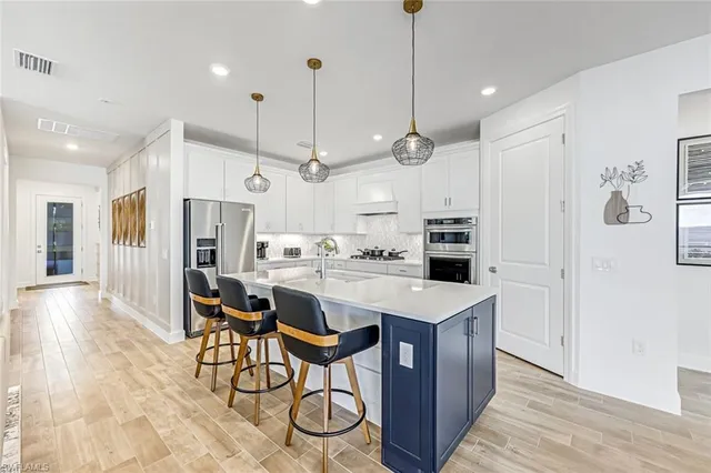 a kitchen with stainless steel appliances a stove a refrigerator a kitchen island with a refrigerator