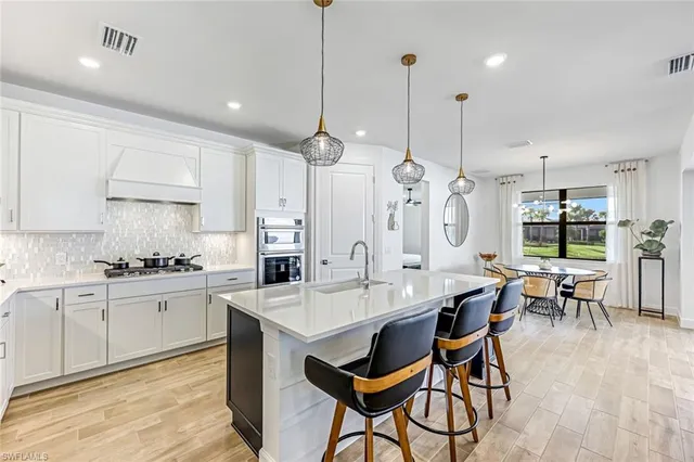a large kitchen with kitchen island a dining table chairs and a white cabinets