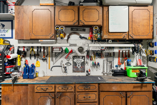 2485 South 1100th Street West Logan, UT 84321 - Photo 26 of 53 Functional workspace featuring wood-finish cabinetry, a white pegboard for organization, and a durable workbench surface