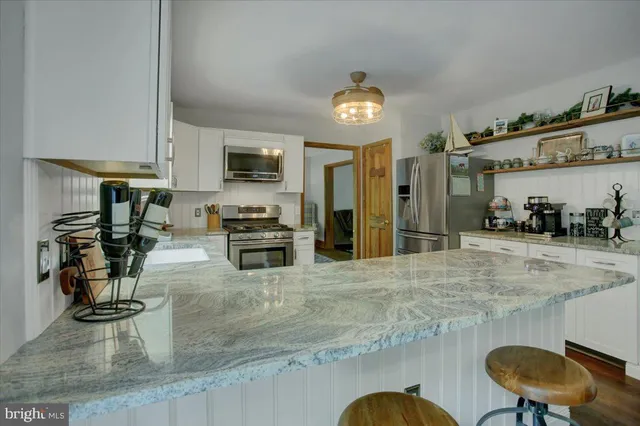 a kitchen with stainless steel appliances granite countertop a sink a stove and a refrigerator