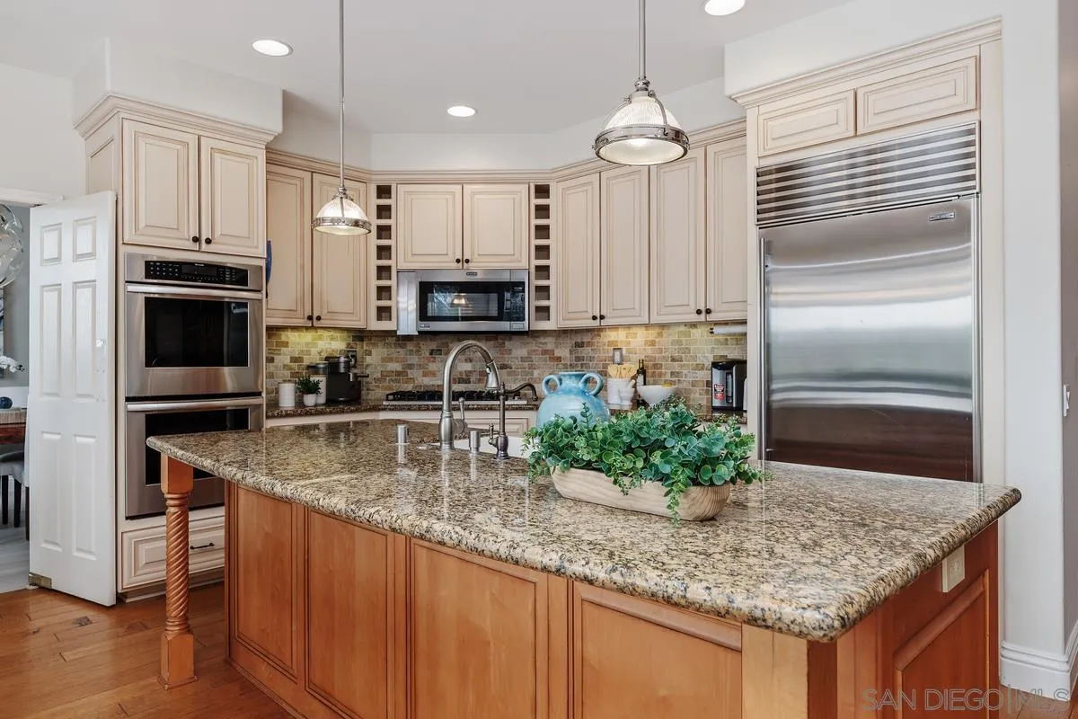 6943 Wildrose Terrace Carlsbad, CA 92011 - Photo 13 of 34 a kitchen with kitchen island granite countertop a sink a counter space appliances and cabinets
