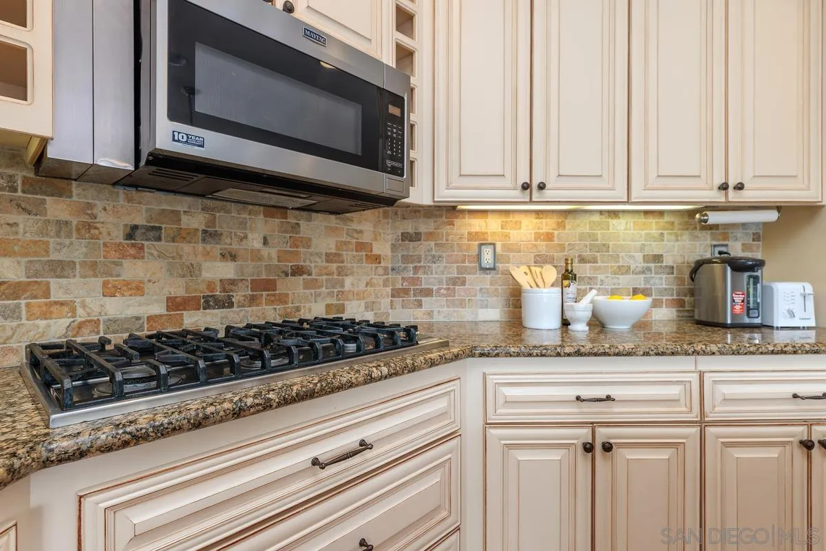 6943 Wildrose Terrace Carlsbad, CA 92011 - Photo 16 of 34 a kitchen with granite countertop white cabinets and stainless steel appliances