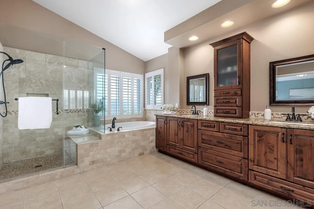 6943 Wildrose Terrace Carlsbad, CA 92011 - Photo 27 of 34 a spacious bathroom with a granite countertop double vanity sink a mirror and a bathtub