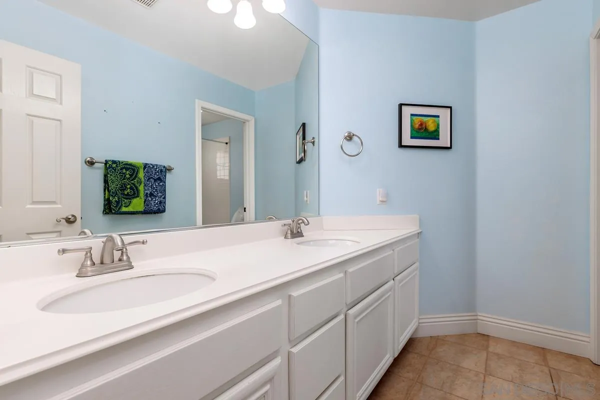 6943 Wildrose Terrace Carlsbad, CA 92011 - Photo 31 of 34 a bathroom with a double vanity sink and a mirror