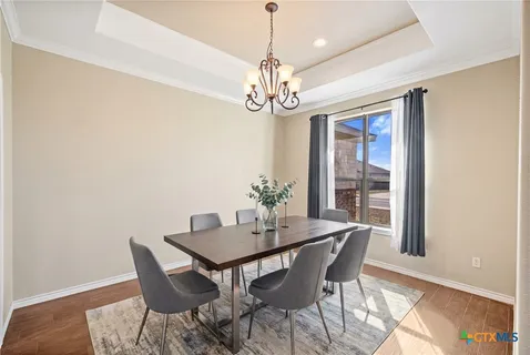 a dining room with wooden floor a chandelier a wooden table and chairs