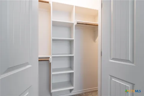 a view of walk in closet with empty racks