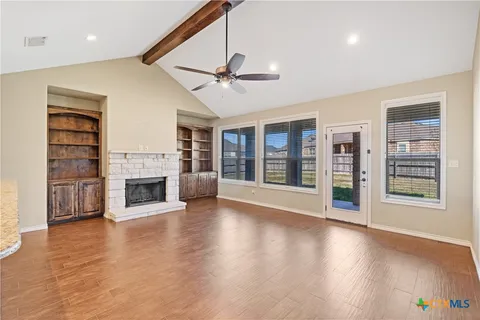 a view of an empty room with wooden floor fireplace and a window