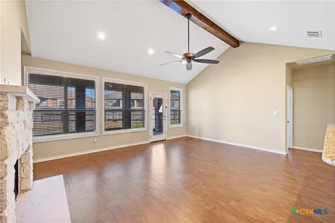 a view of an empty room with a window and wooden floor