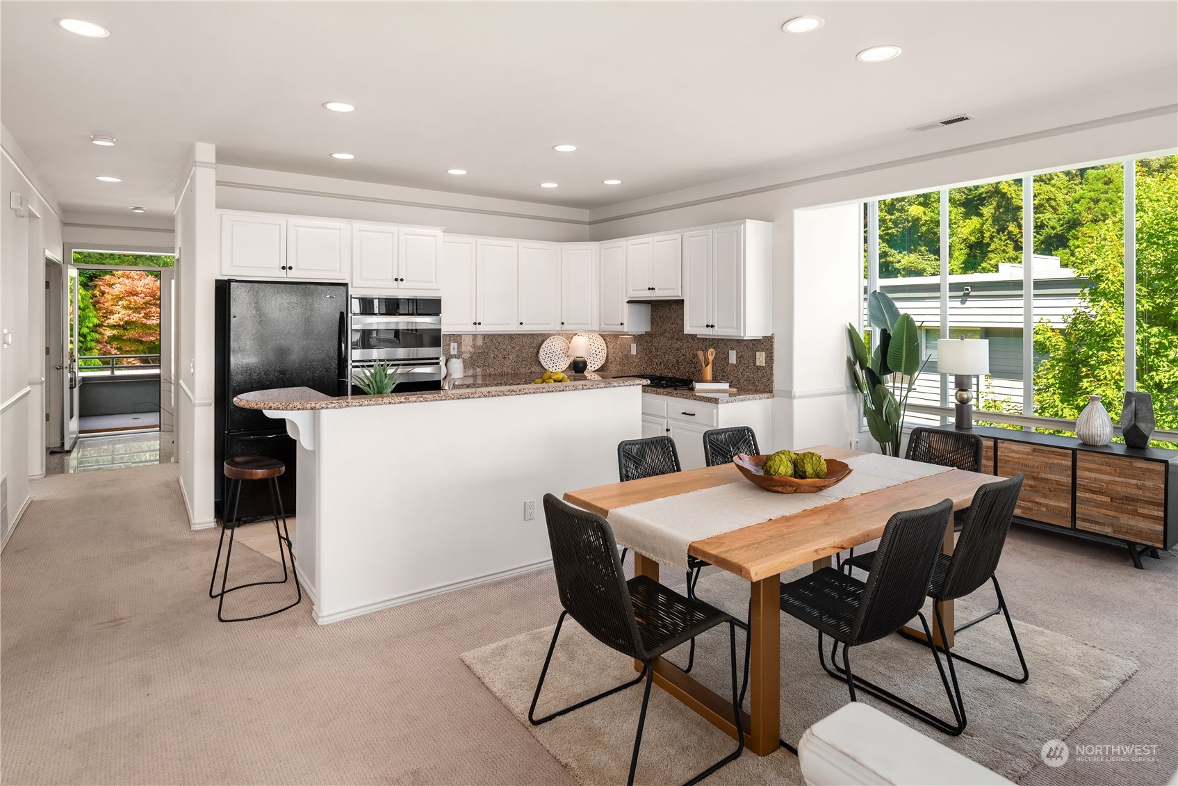 2349 Harbor Avenue Southwest, Unit 705 Seattle, WA 98126 - Photo 11 of 34 a kitchen with stainless steel appliances kitchen island granite countertop a table chairs and a refrigerator